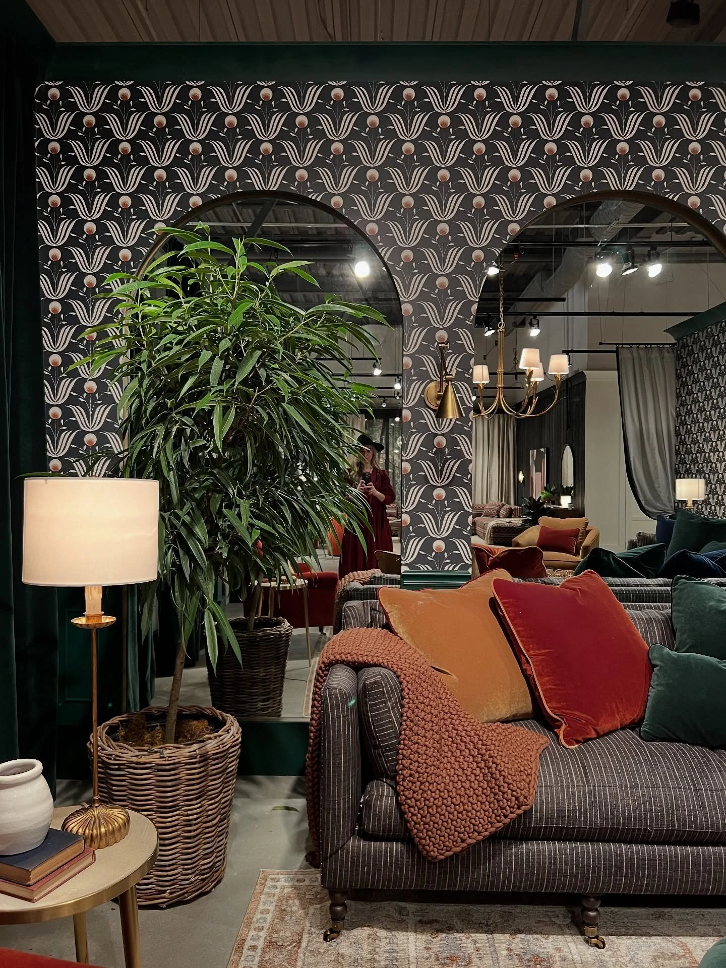 Patterned wallpaper and arched mirrors behind layered pillows