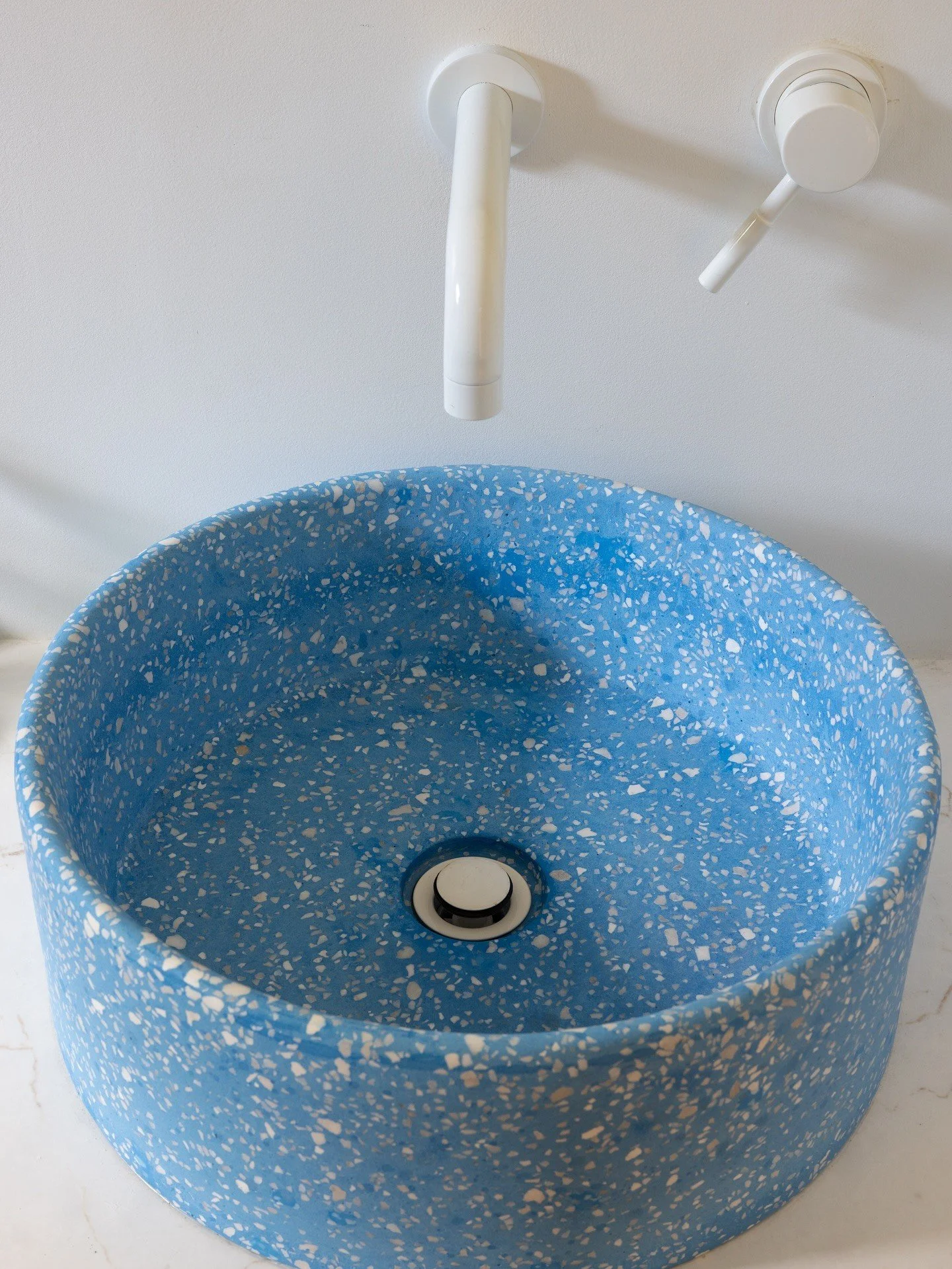 Close-up of blue terrazzo vessel basin and white drain