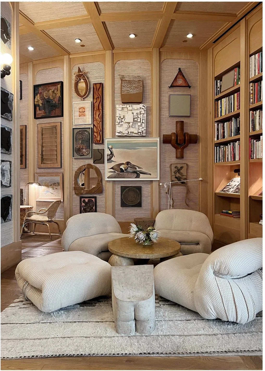 Curved upholstered chairs beneath framed art and tall wood shelves