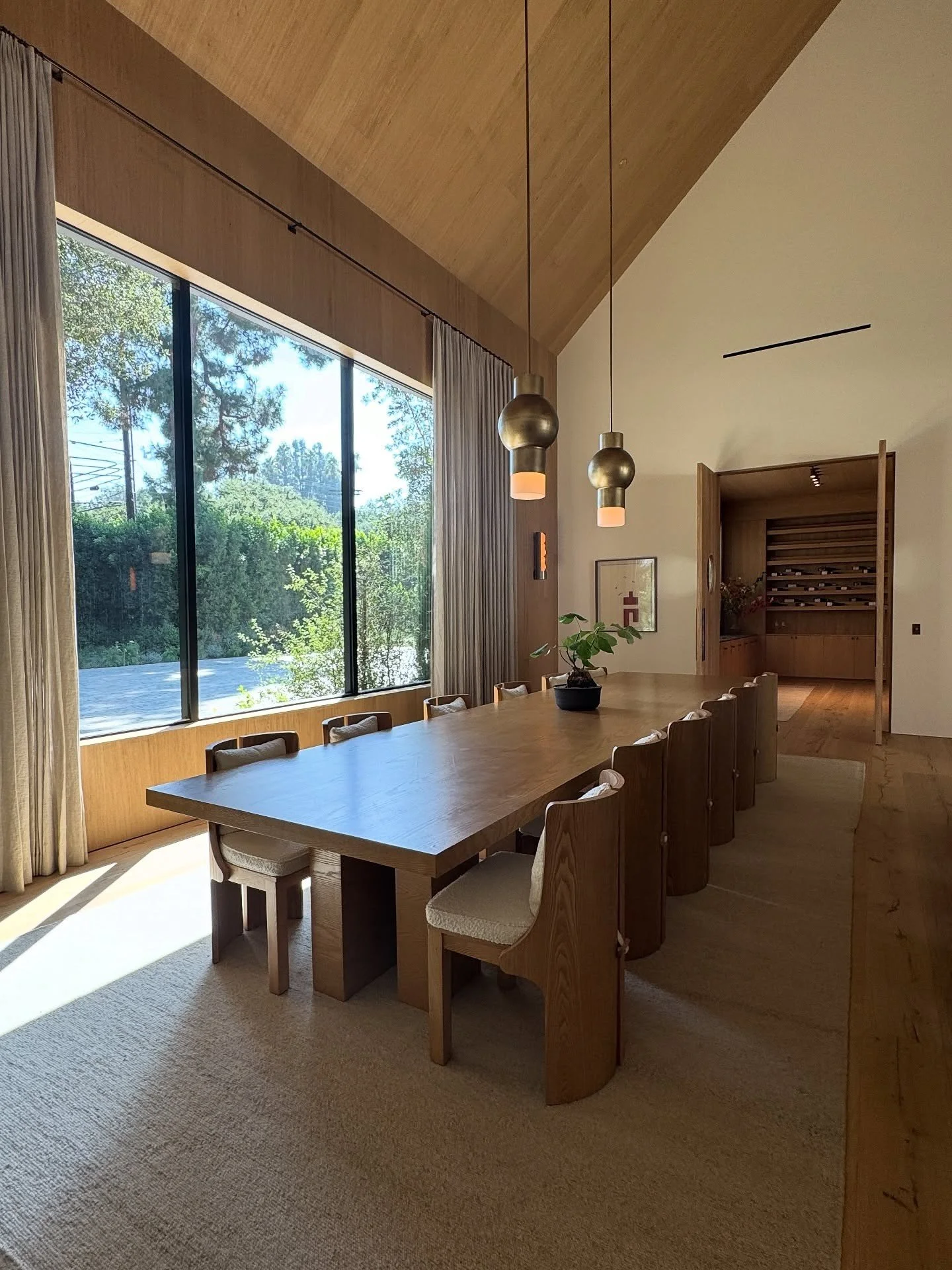 Long dining table beside full-height garden glazing