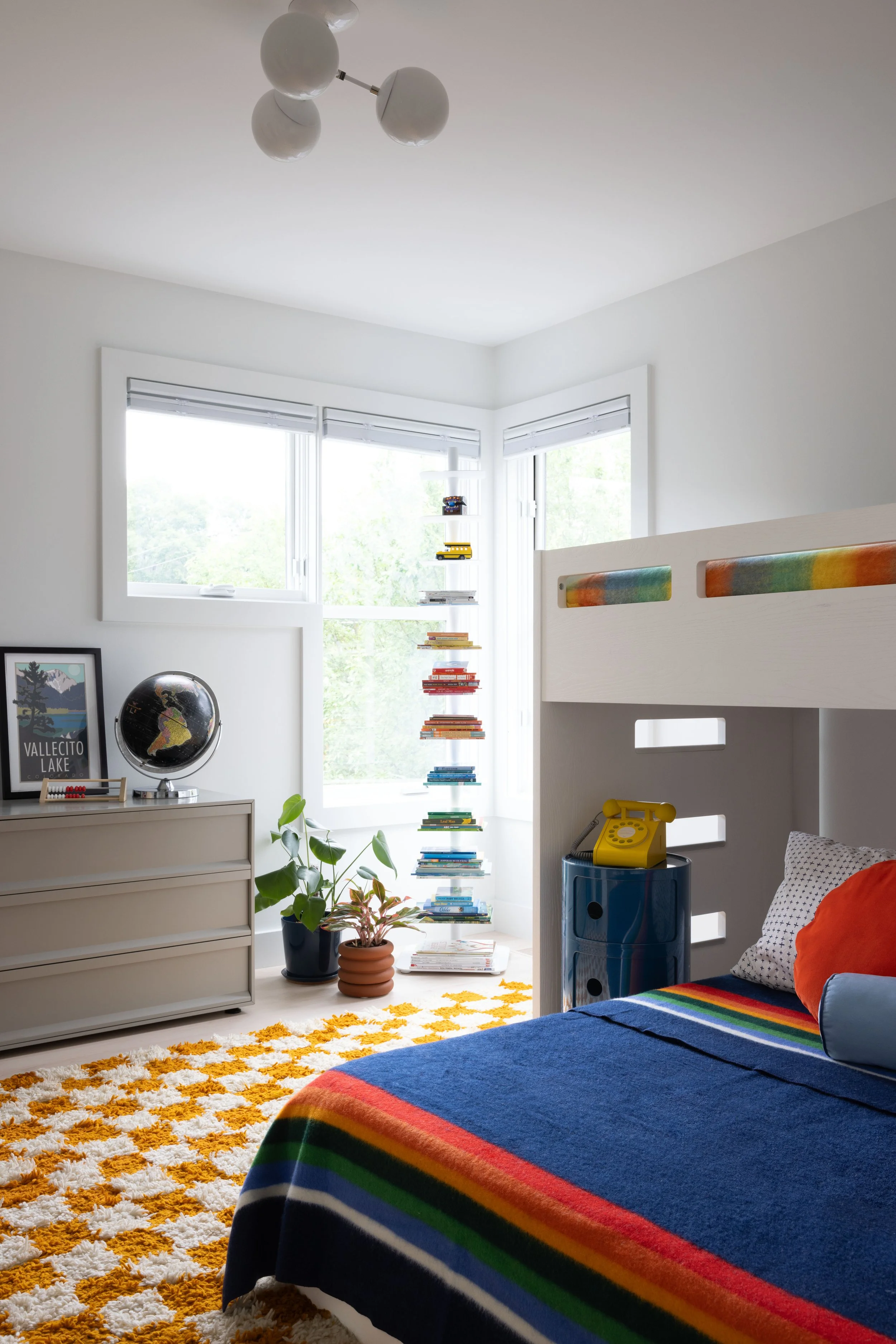 Child’s bedroom with a loft bed, striped bedding, and patterned yellow rug.