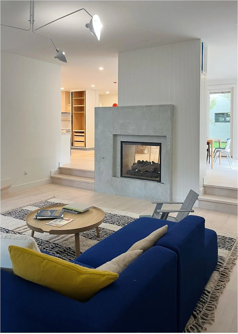 Blue sofa facing a gray fireplace in a light-filled white living room