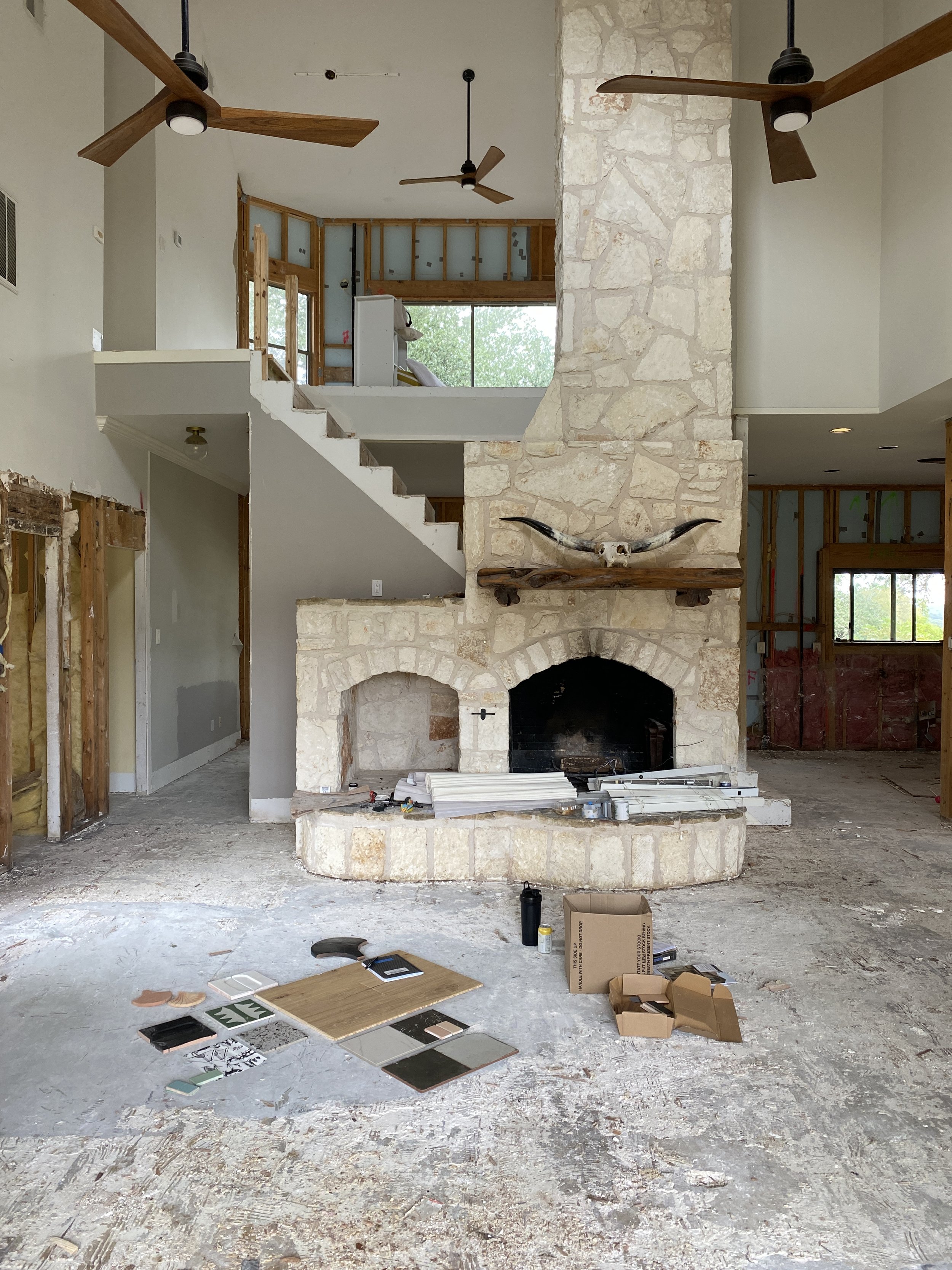 Living room under renovation with a stone fireplace and exposed walls.