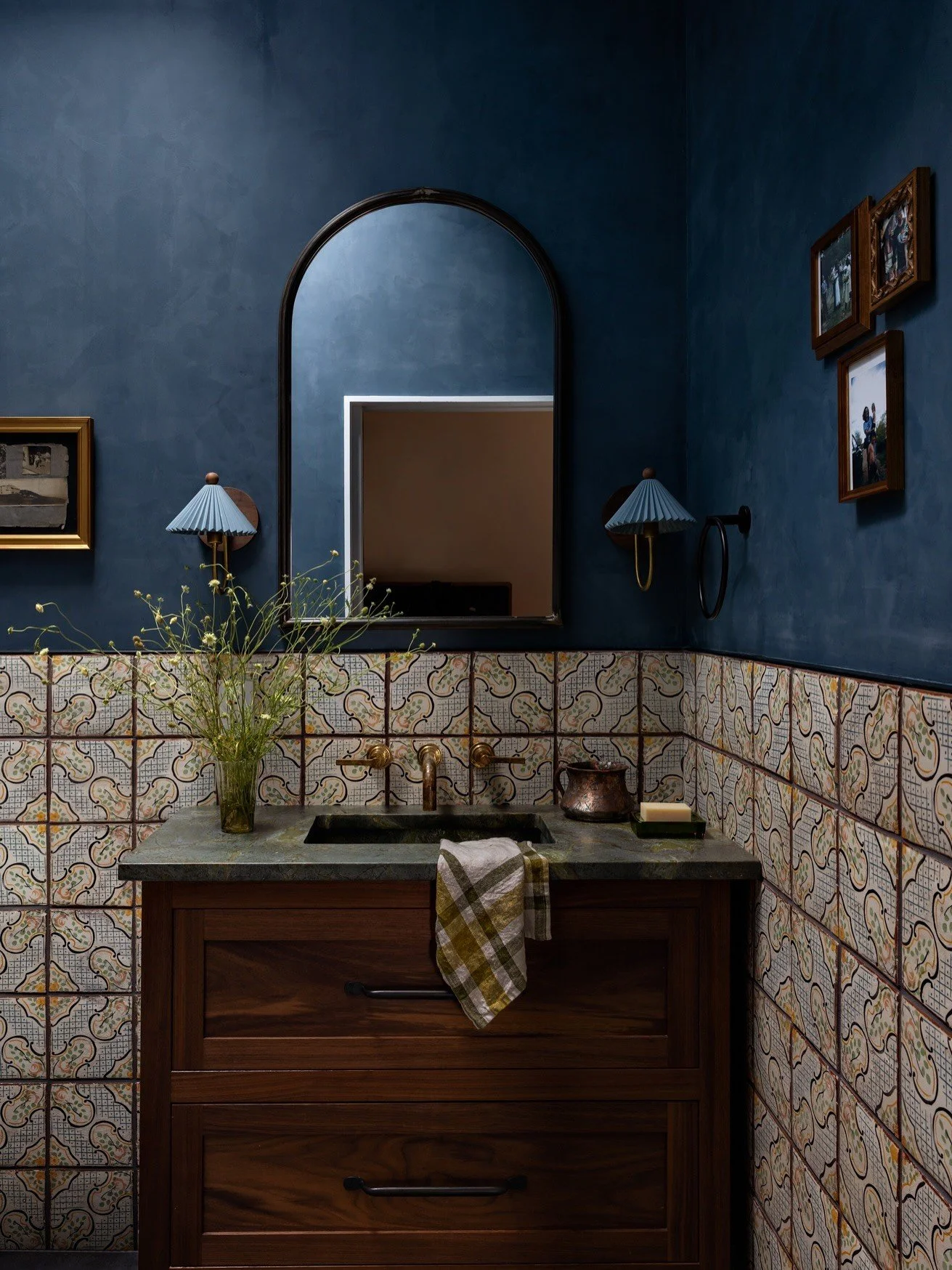 Deep blue powder room above patterned tile and wood vanity