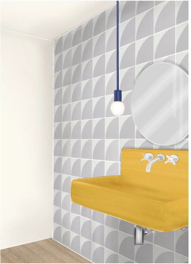 Yellow wall-hung basin against large gray-and-white geometric tiles