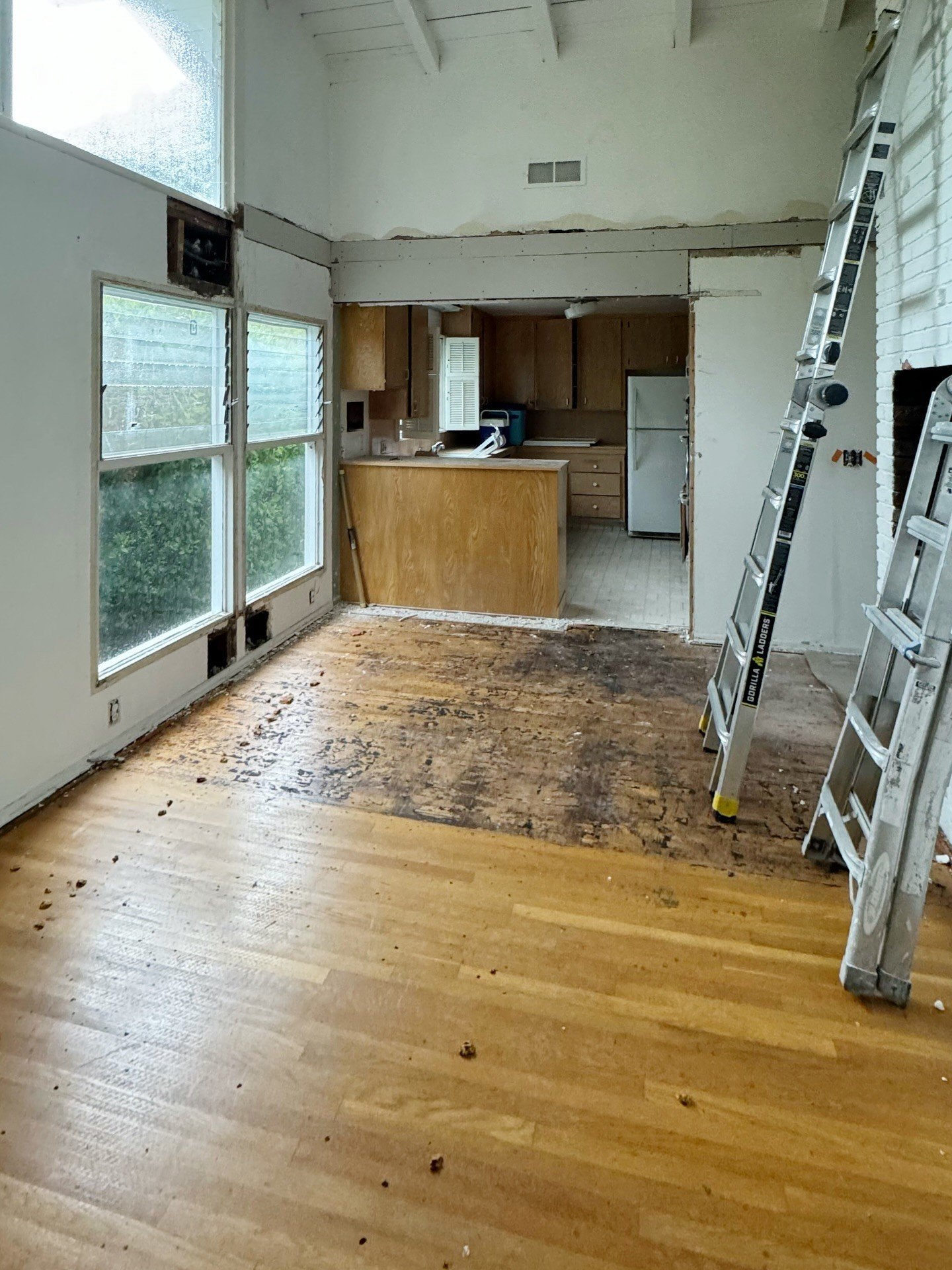 Kitchen renovation in progress with stripped walls and wood flooring