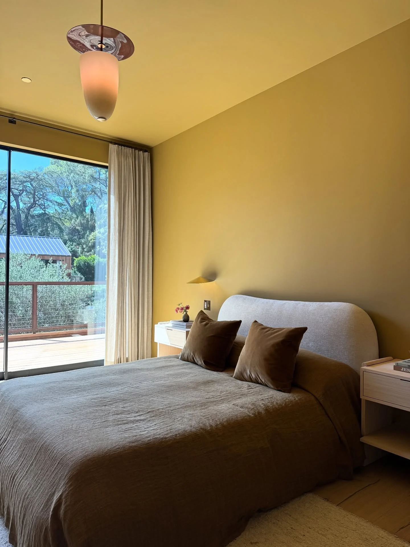 Yellow bedroom with a curved headboard and pendant light