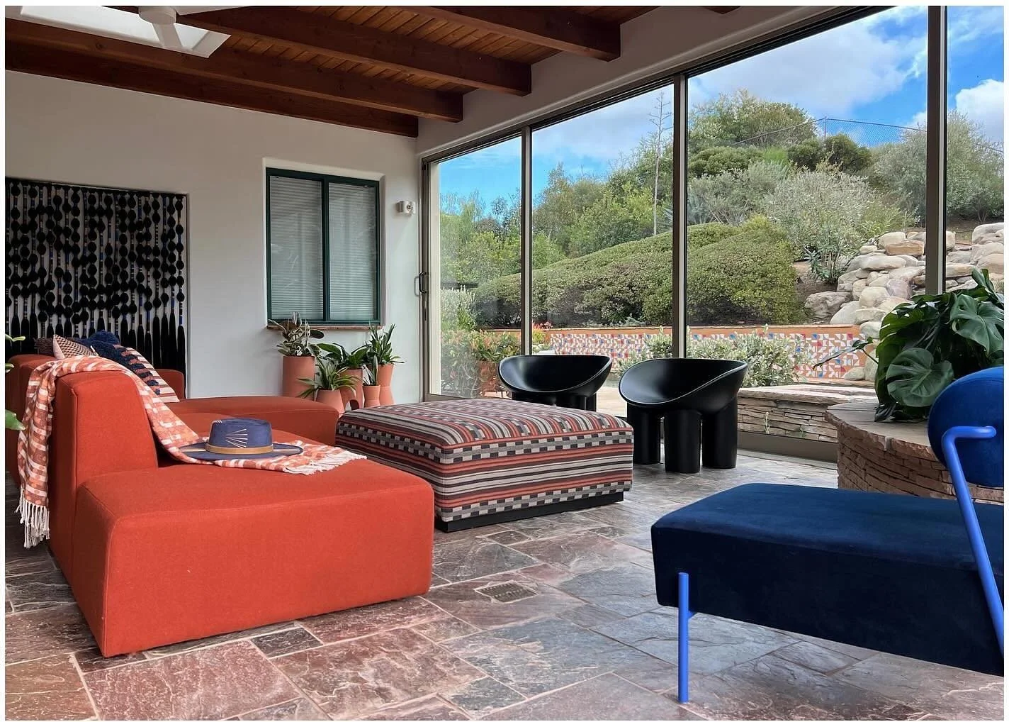 Outdoor lounge with orange sofa blue chair and mountain views