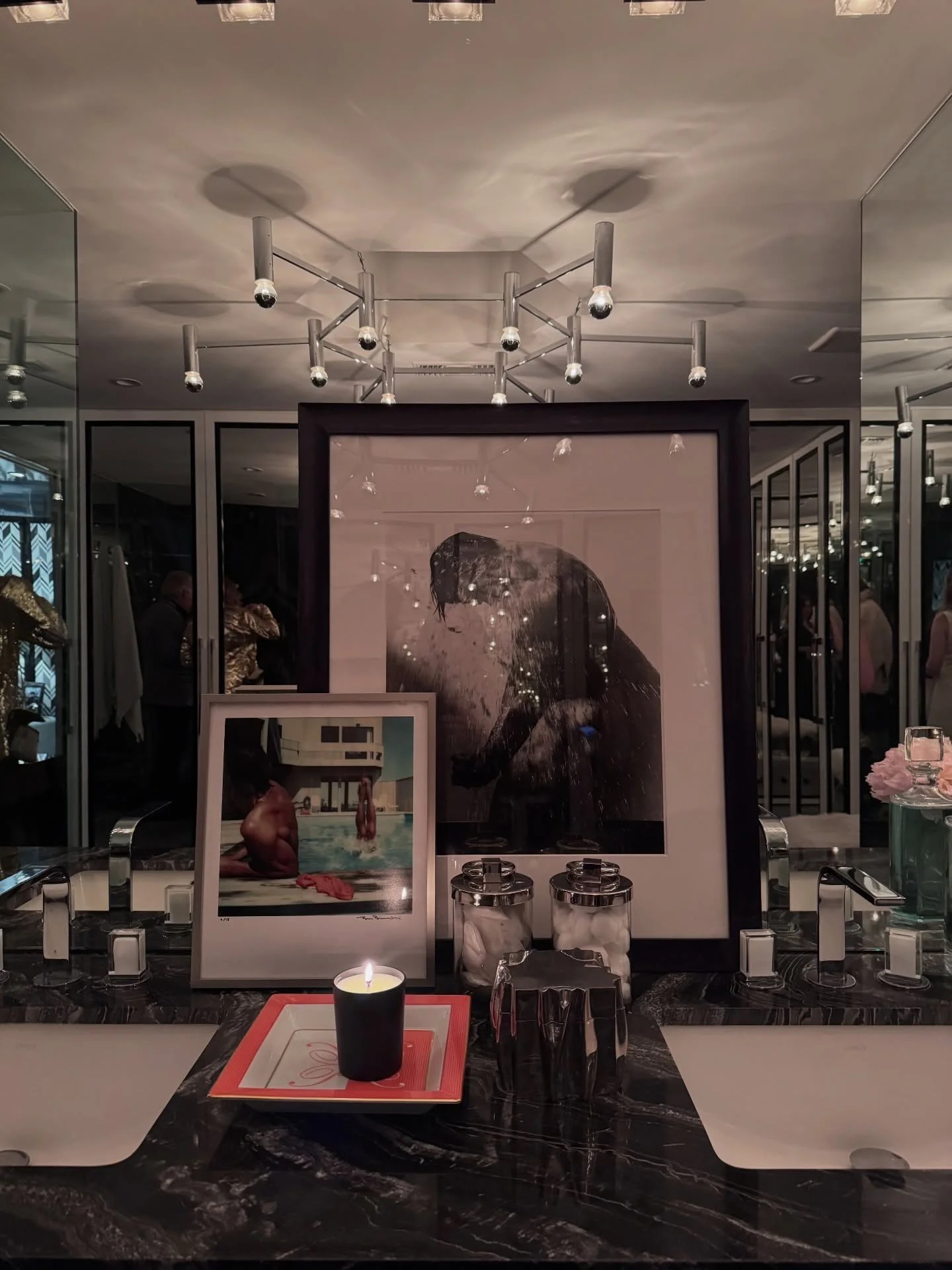 Art and perfume bottles reflected in a mirrored bathroom