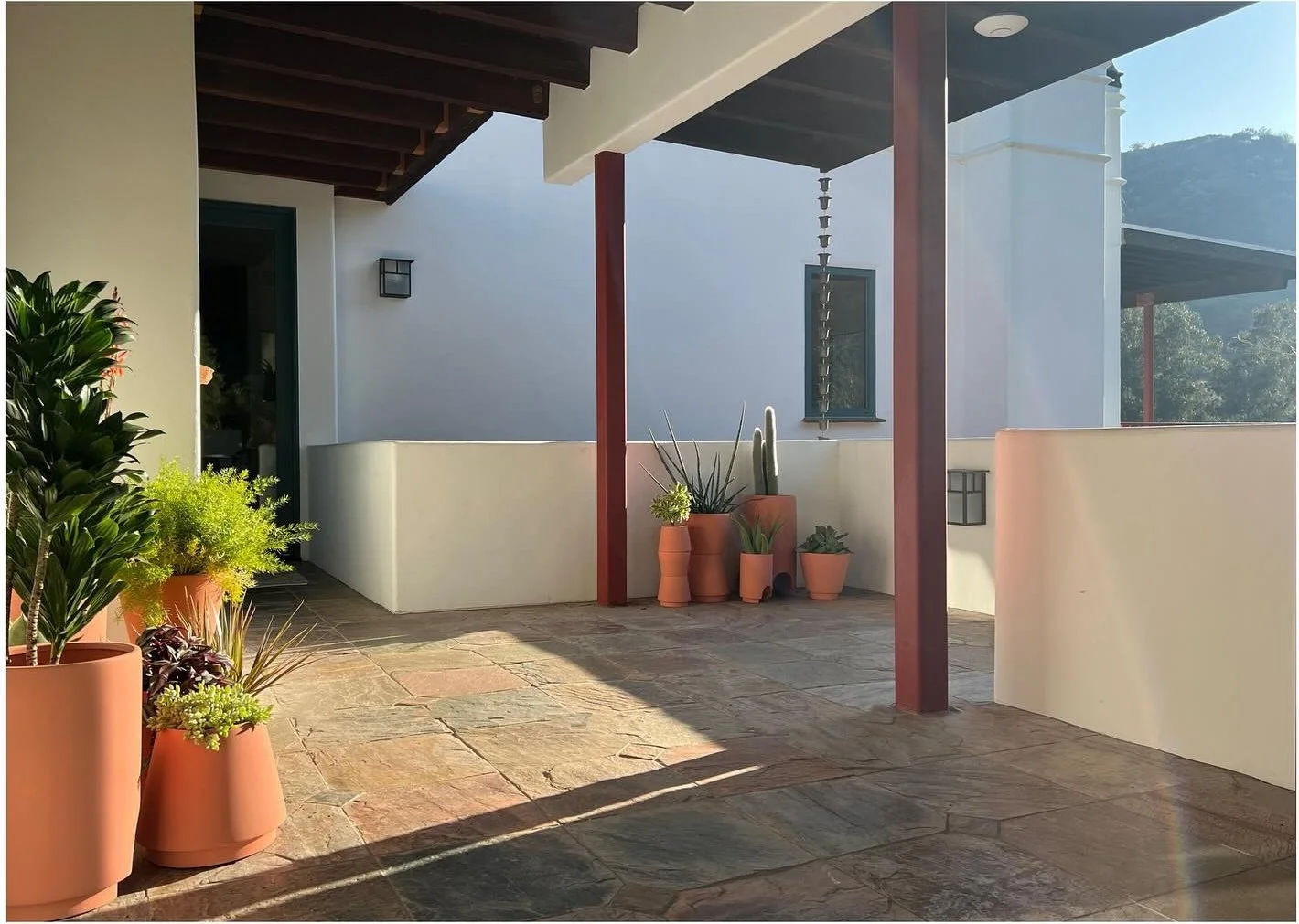 Terracotta pots along a sheltered terrace with timber posts