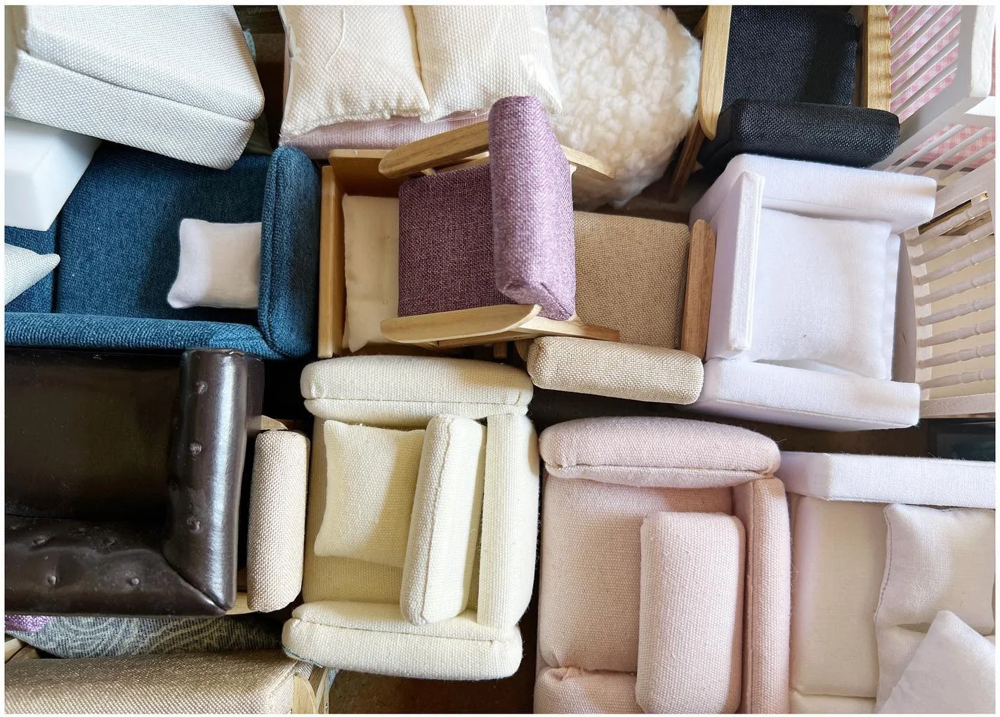 Collection of miniature upholstered chairs and sofas in assorted pale textiles