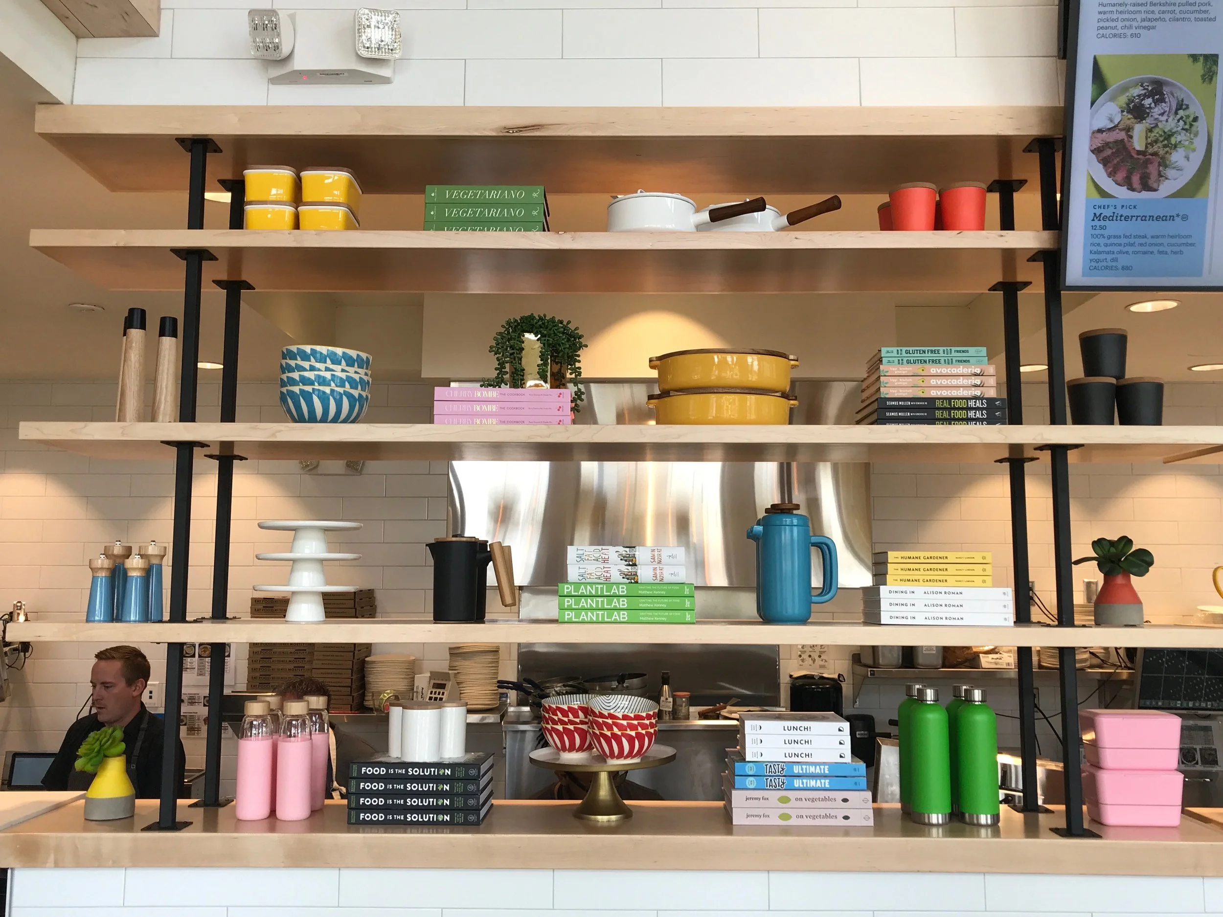 Restaurant shelves displaying colorful dishes, bottles, and books.