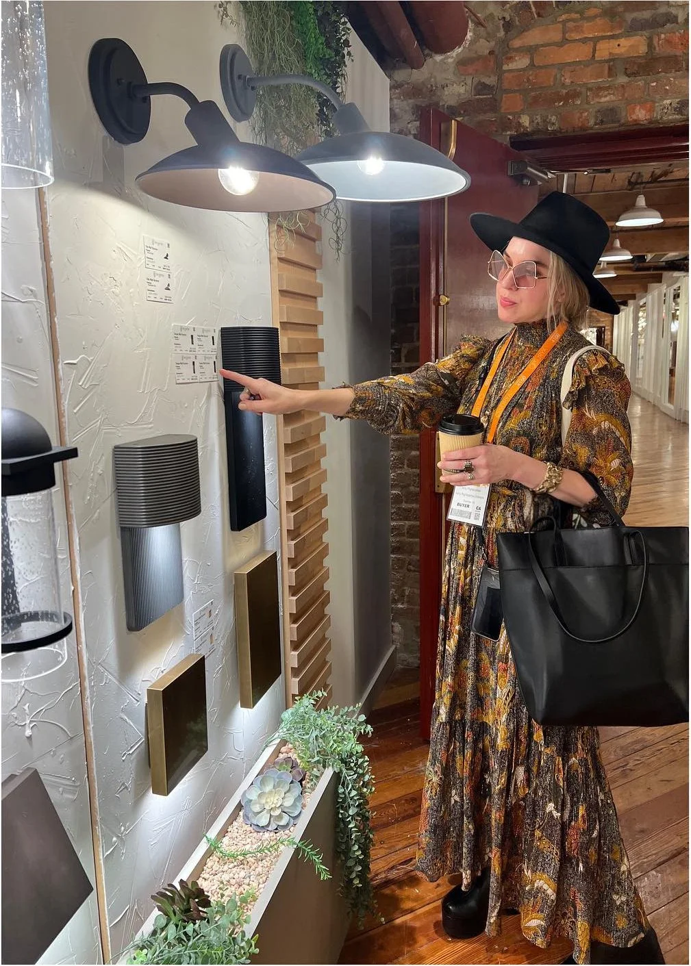 Designer comparing wall-mounted lighting samples beside exposed brick