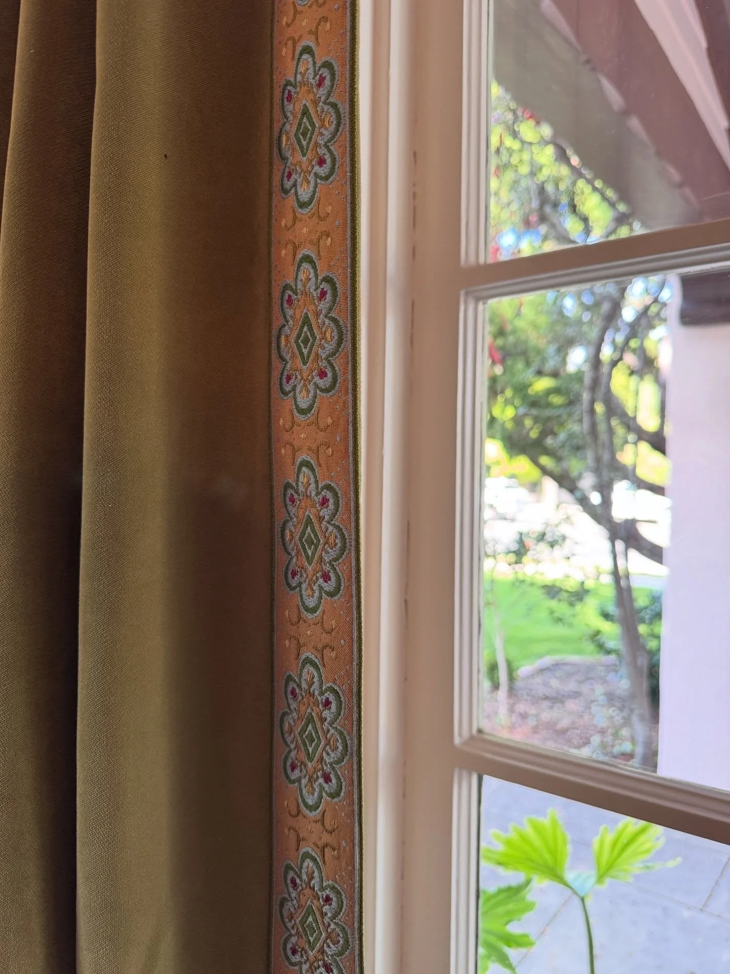 Decorative painted window trim beside a cream curtain
