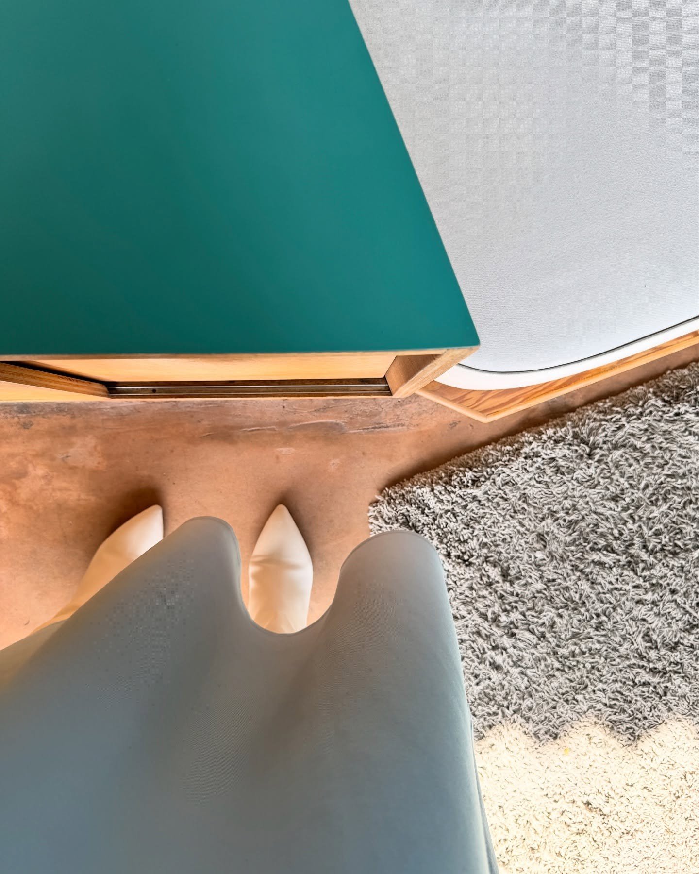 Close view of a sculptural seat beside turquoise paneling and a window