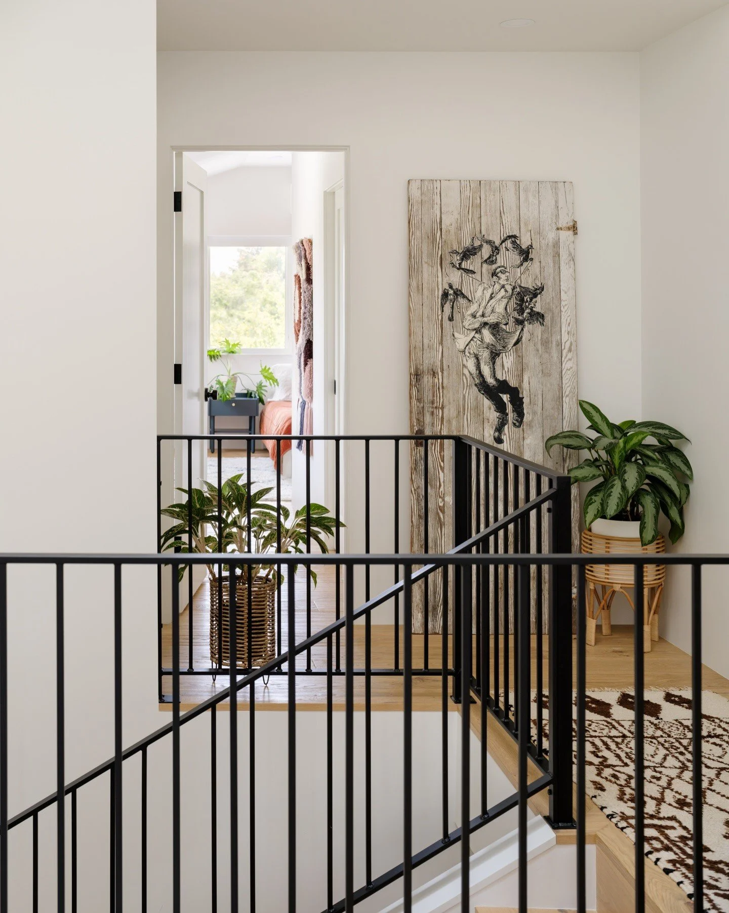 Bright stair landing with black rails, artwork and plants