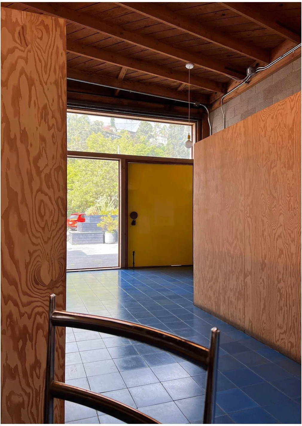 Plywood-lined studio passage opening toward a bright yellow doorway