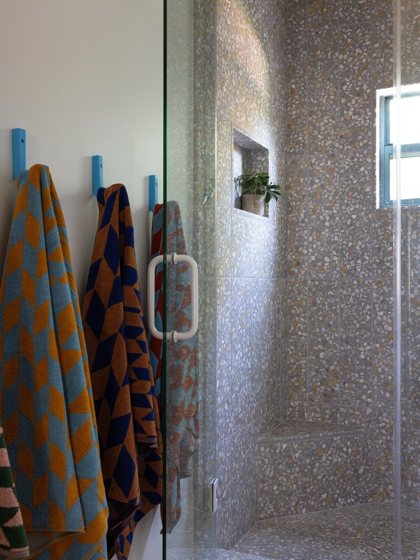 Terrazzo shower wall with colorful towels and a glass screen