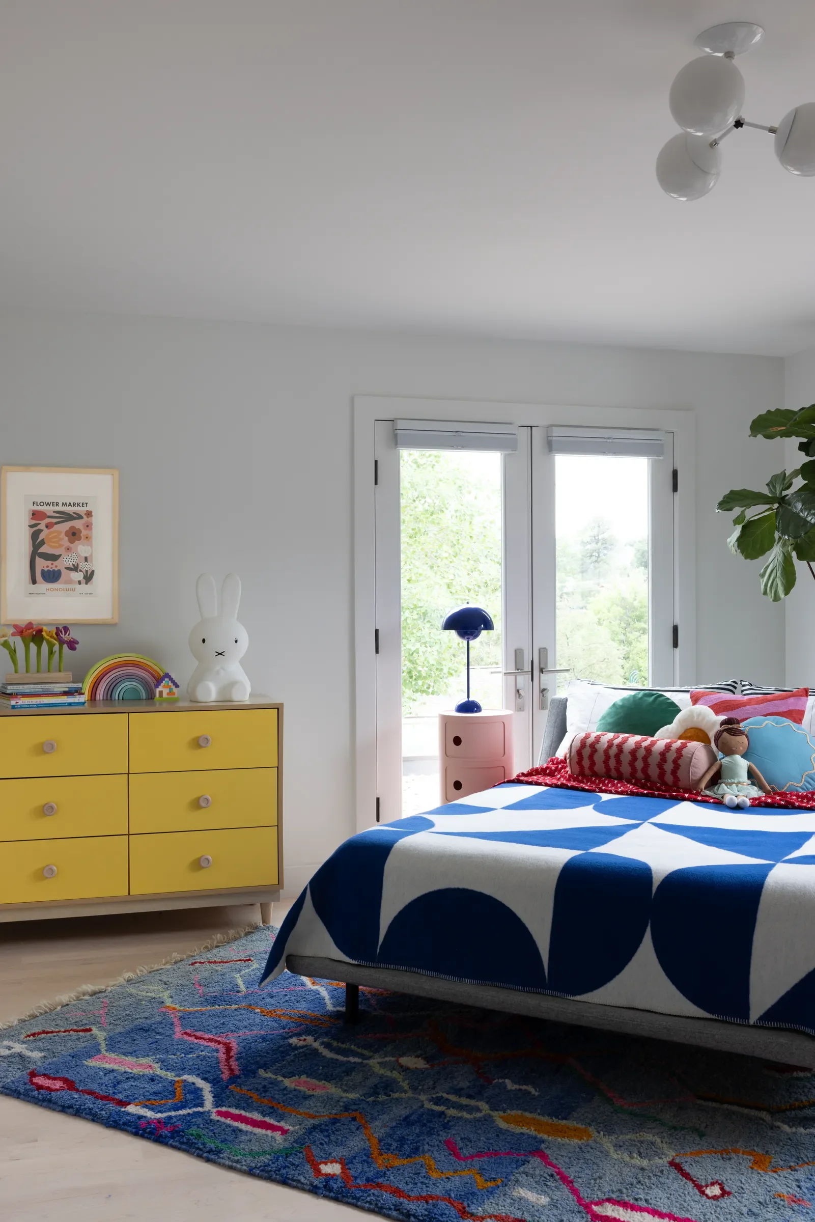 Colorful child’s bedroom with a yellow dresser and blue-and-white patterned bedding.