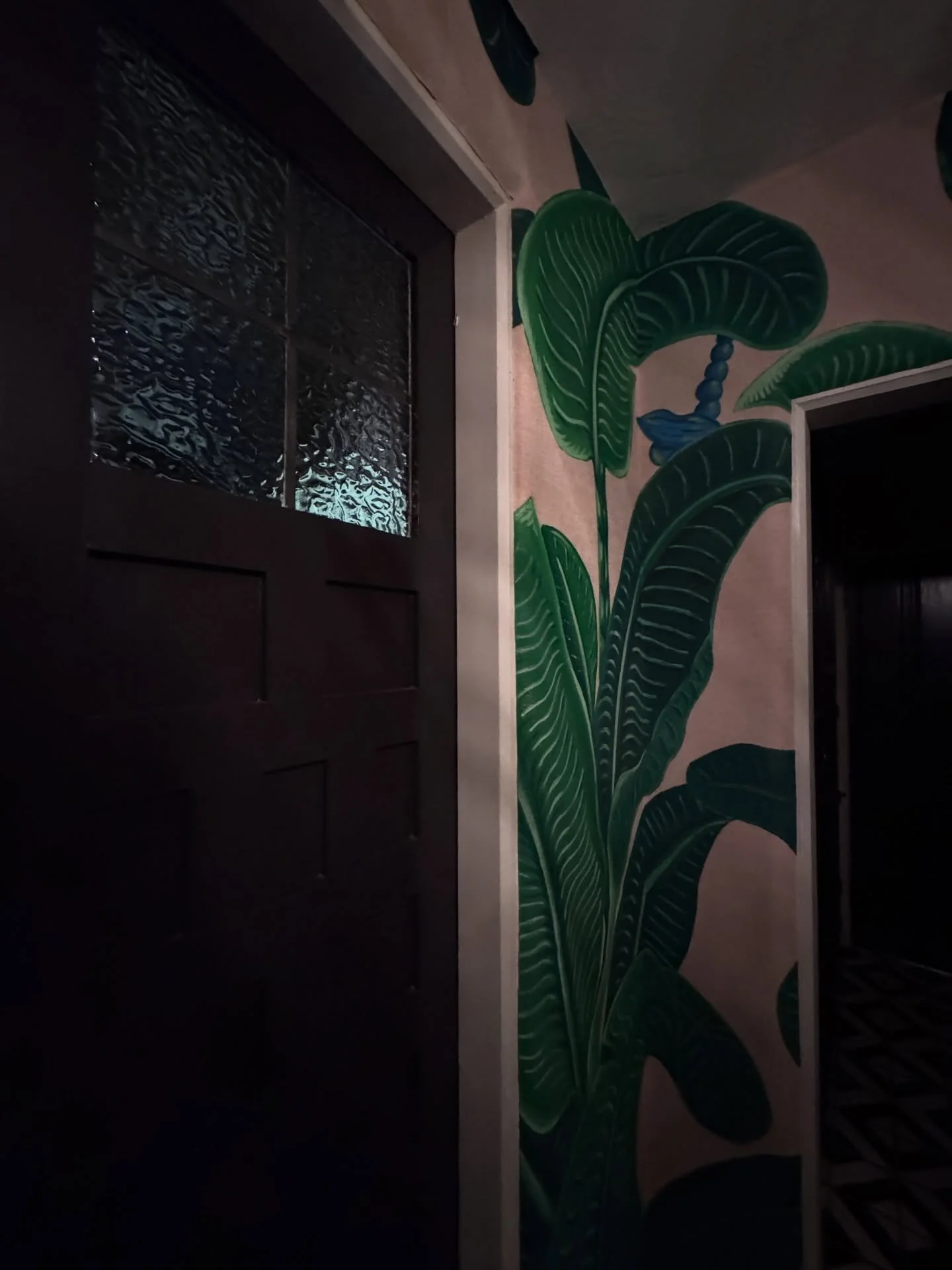 Banana-leaf wallpaper beside a dark paneled doorway