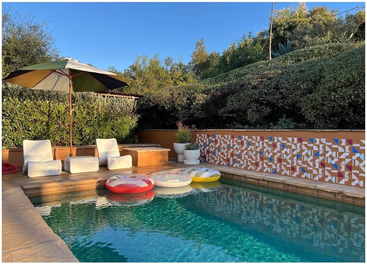 Swimming pool with colorful floats and a tiled garden retaining wall