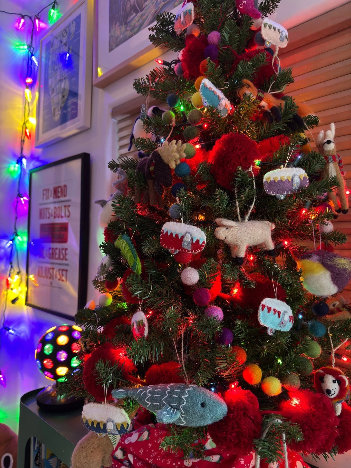 Christmas tree with bright ornaments beside a patterned bed