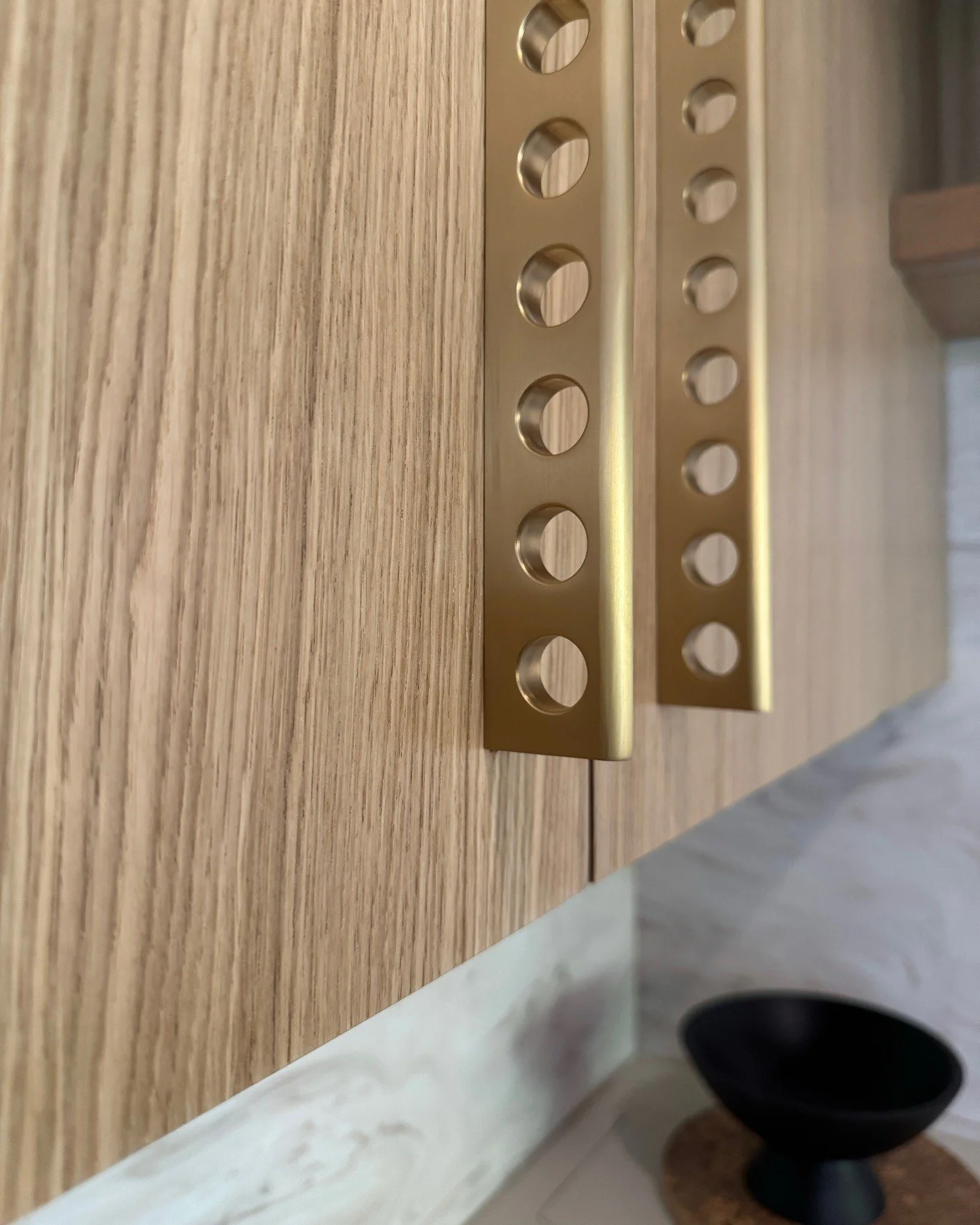 Brass hardware close-up on vertically grained wood cabinetry