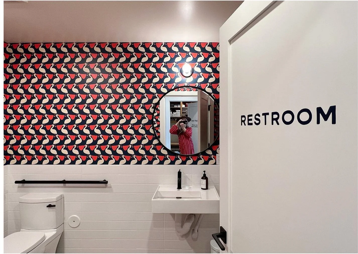 Motel restroom with bold red-and-black wallpaper and white sinks