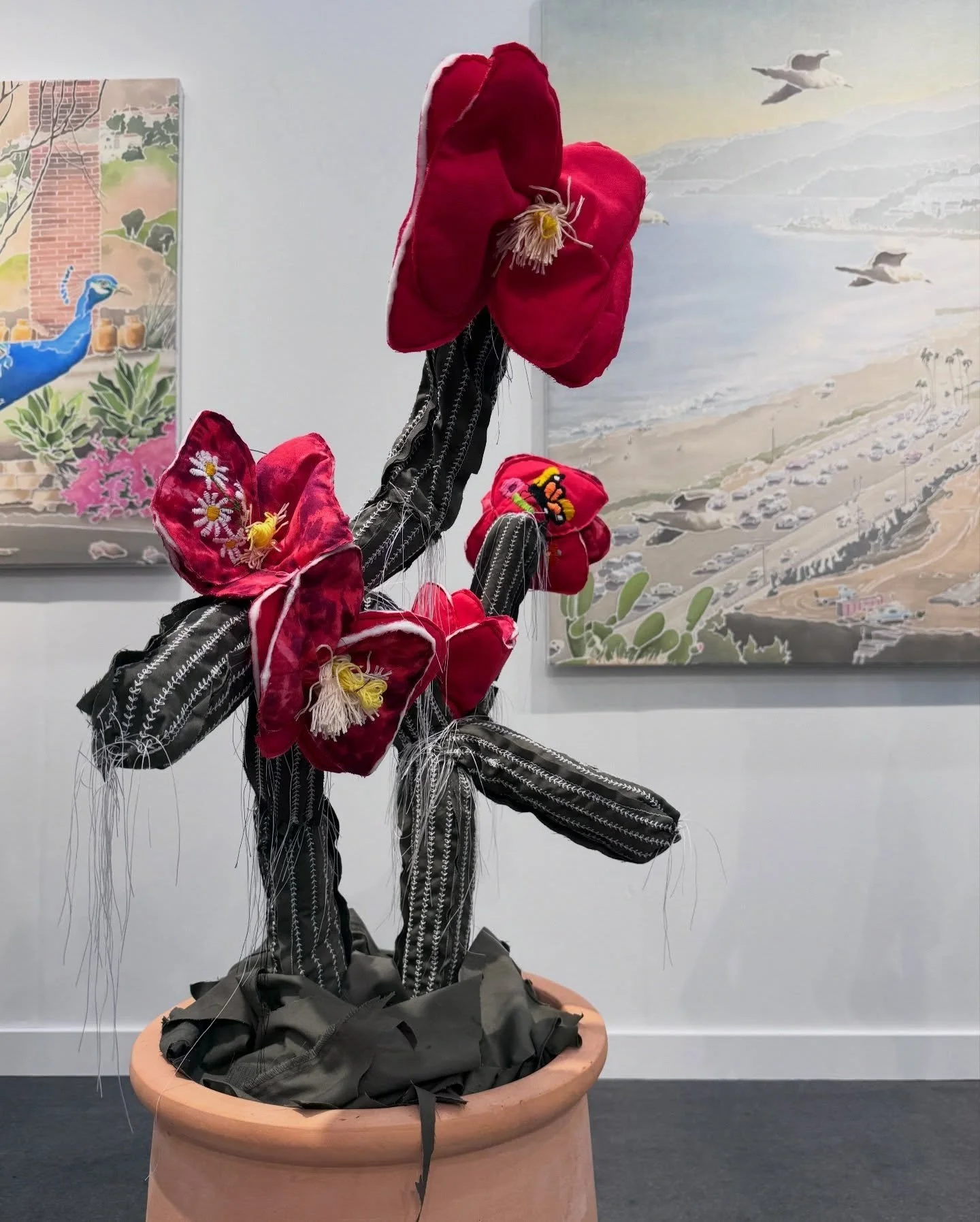 Sculptural red flowers growing from a painted terracotta pot