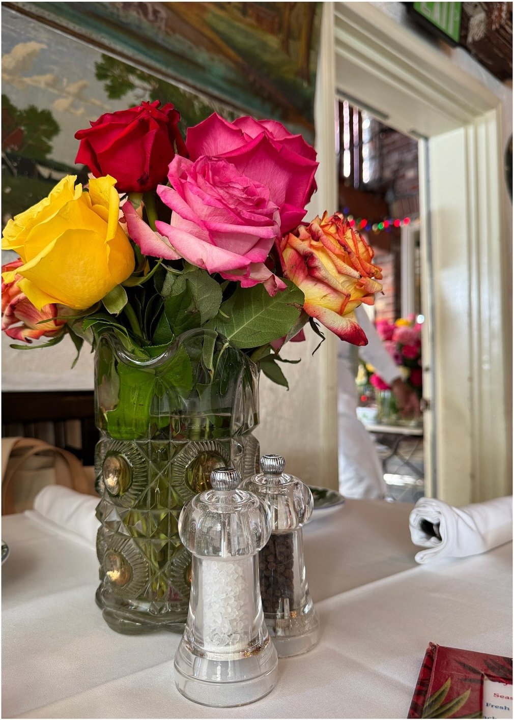 Roses in a glass vase beside a silver table accessory