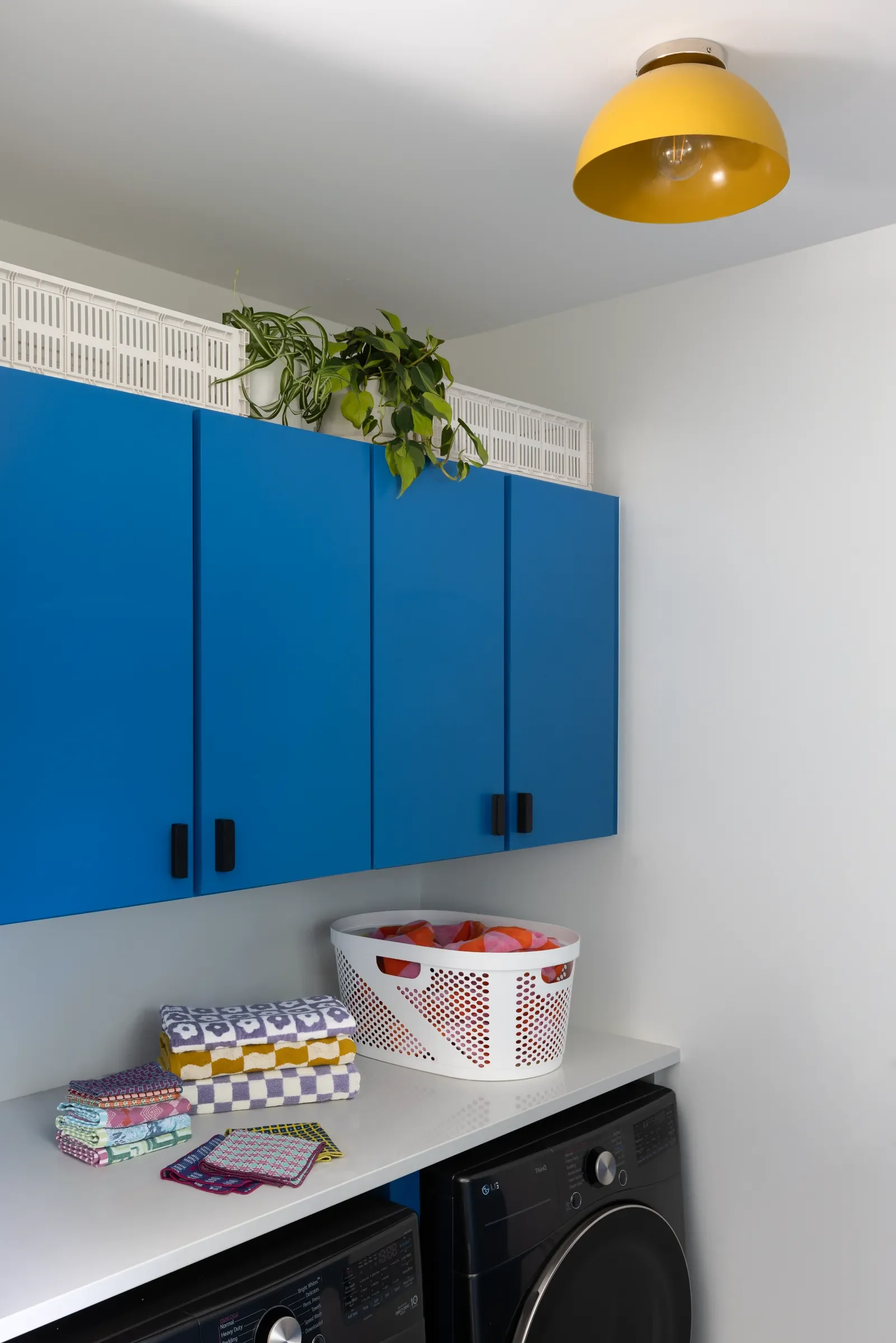 Laundry room with blue cabinets and a yellow ceiling light.