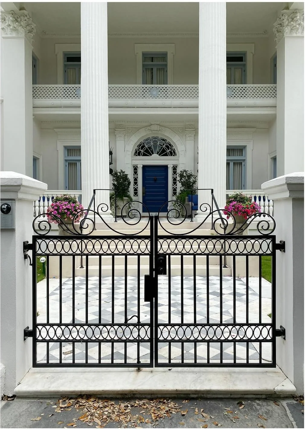 White columned house behind an ornamental iron gate