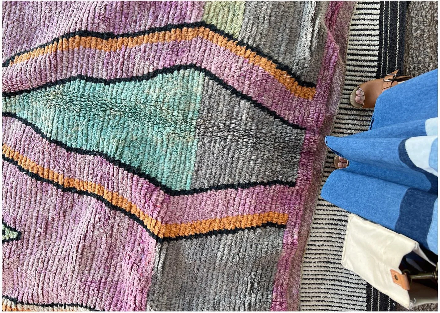 Vintage woven rug with wavy black lines and faded pink and mint bands