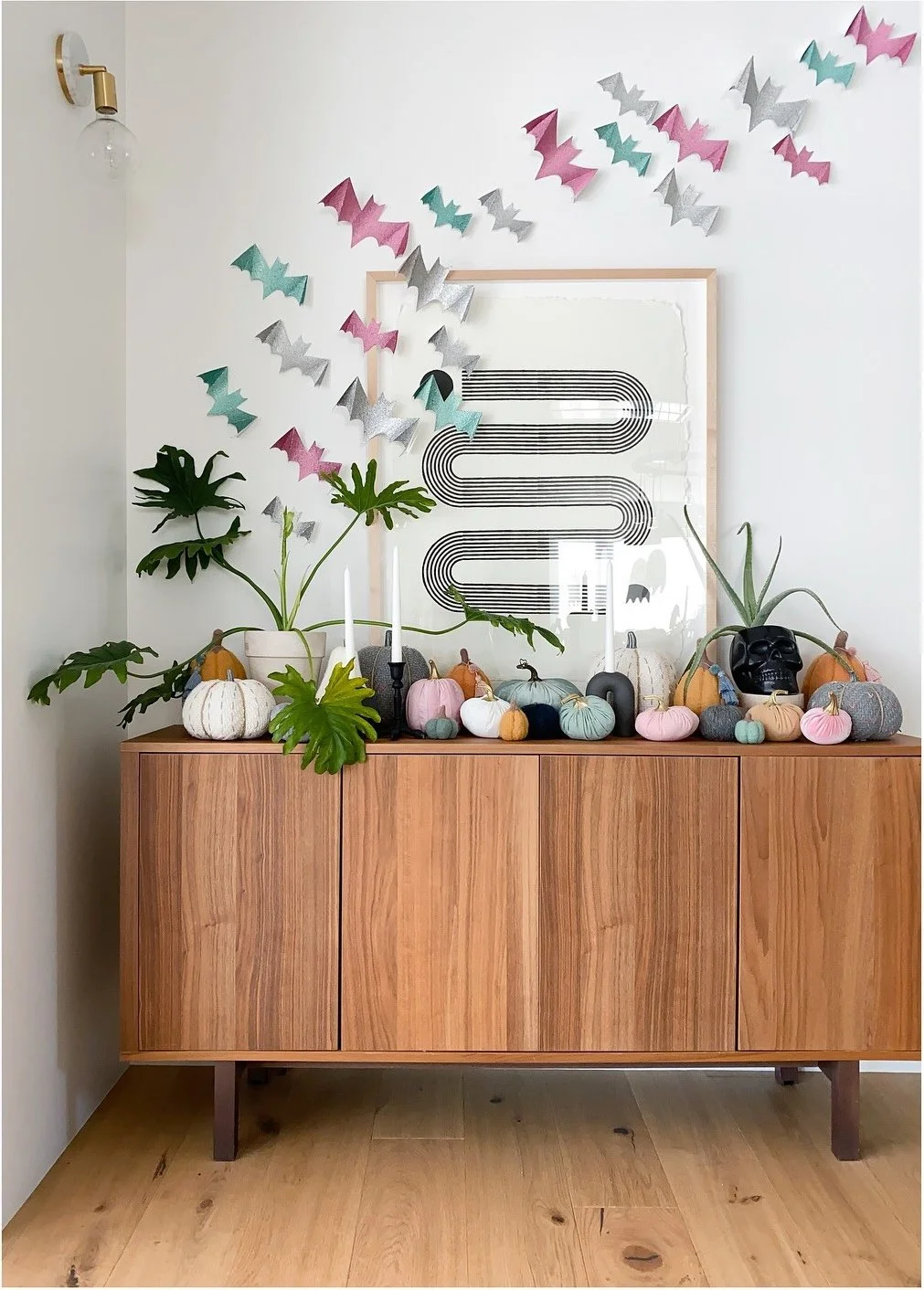 Wood sideboard styled with pastel pumpkins plants and a framed print