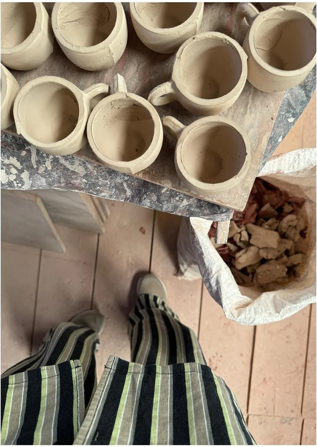 Unfinished ceramic cups arranged on a work surface