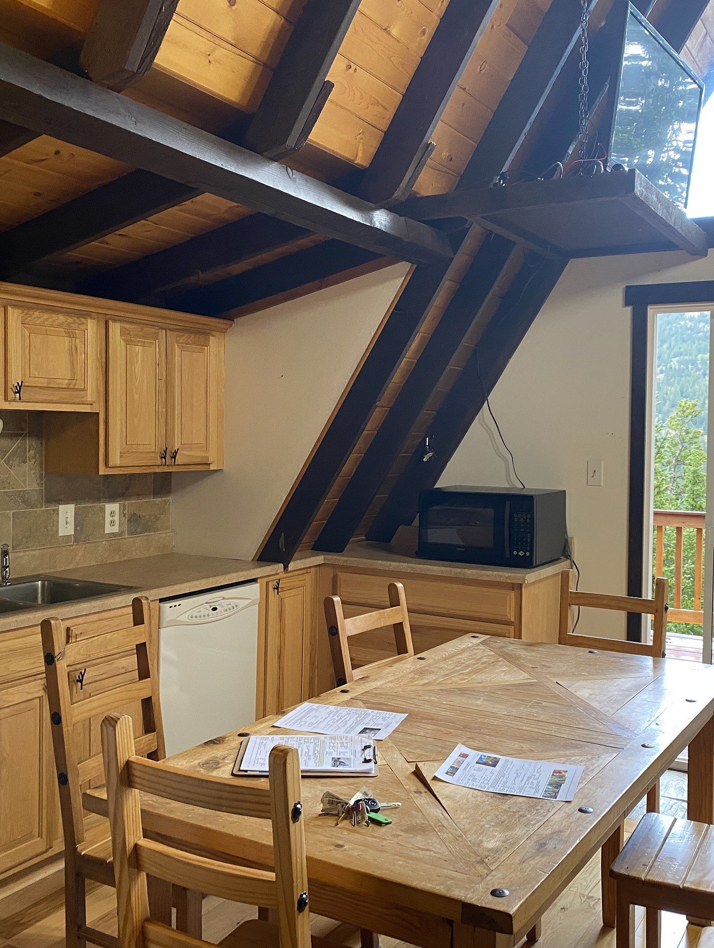 Original A-frame dining area with pine cabinetry and dark roof beams