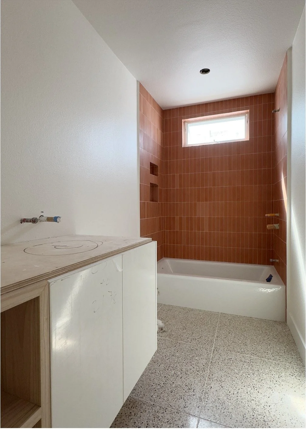 New bathroom with terracotta shower tile and pale vanity
