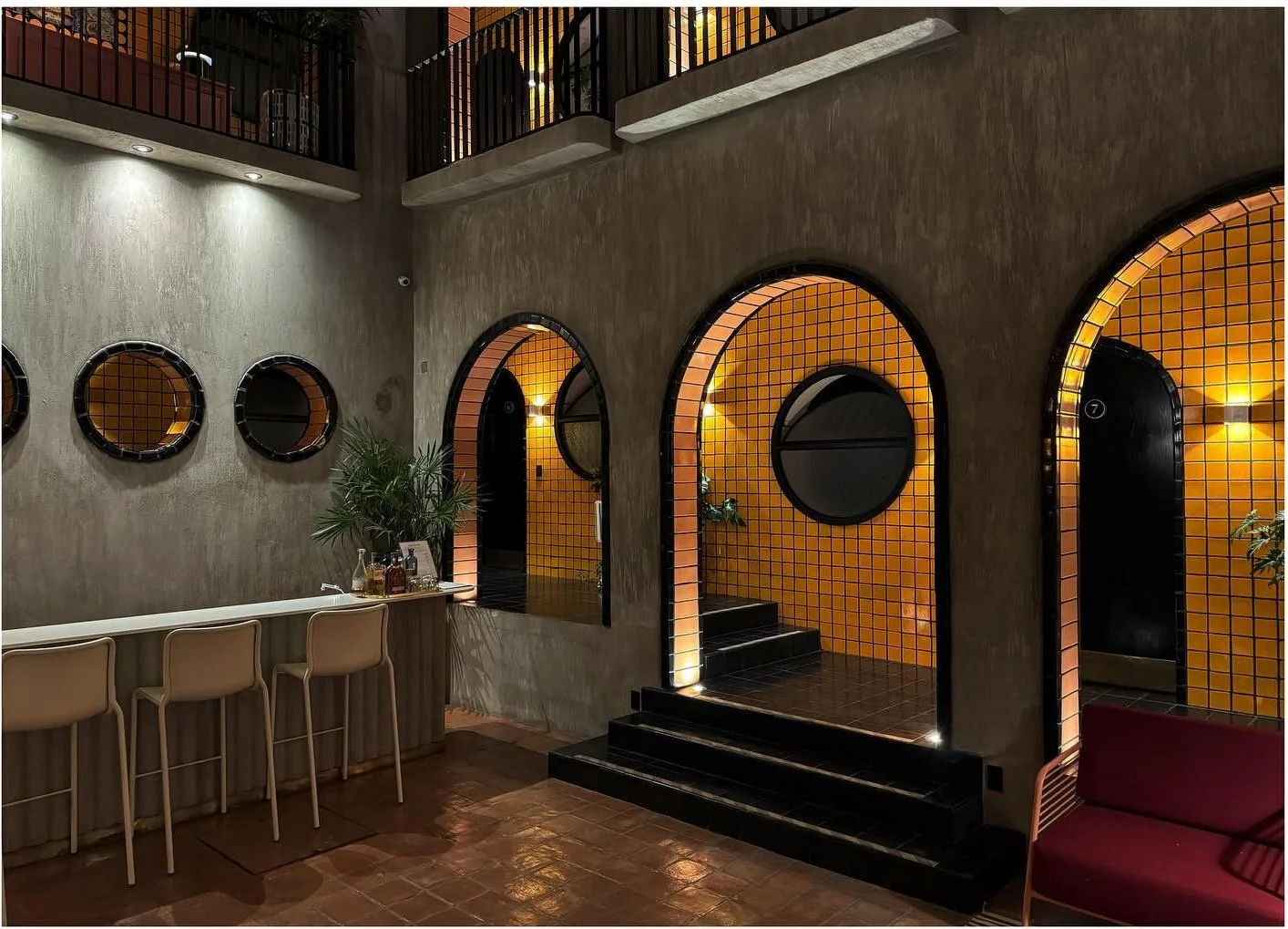 Small bar beneath round mirrors beside a yellow tiled arch