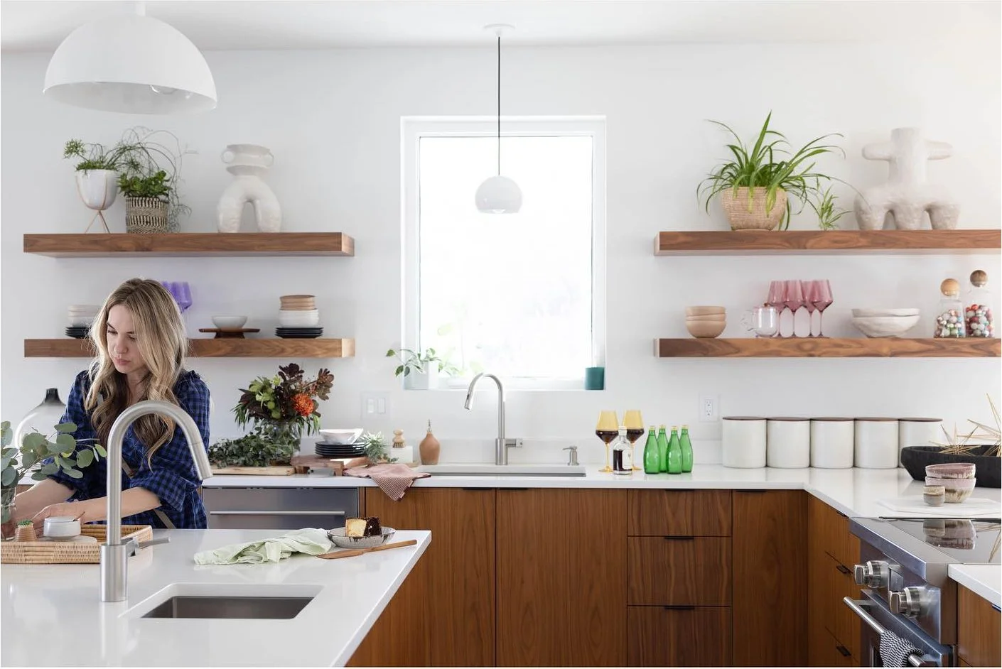 Designer arranging details beside a kitchen island and open wood shelves