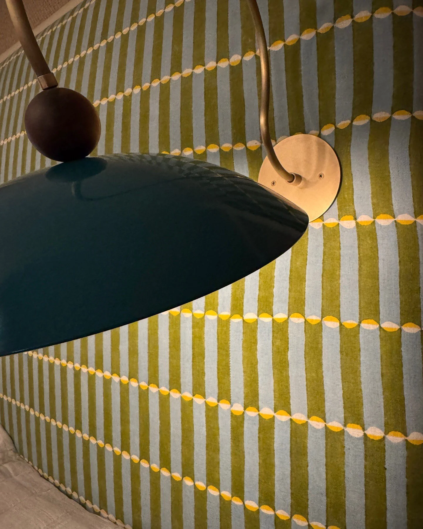 Green pendant light against patterned yellow wall covering