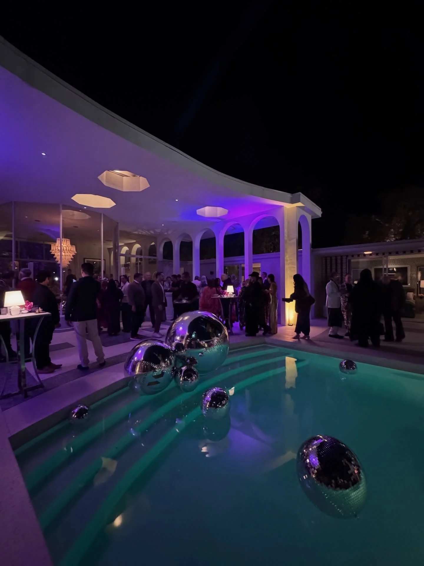 Outdoor entertaining terrace around a brightly lit pool