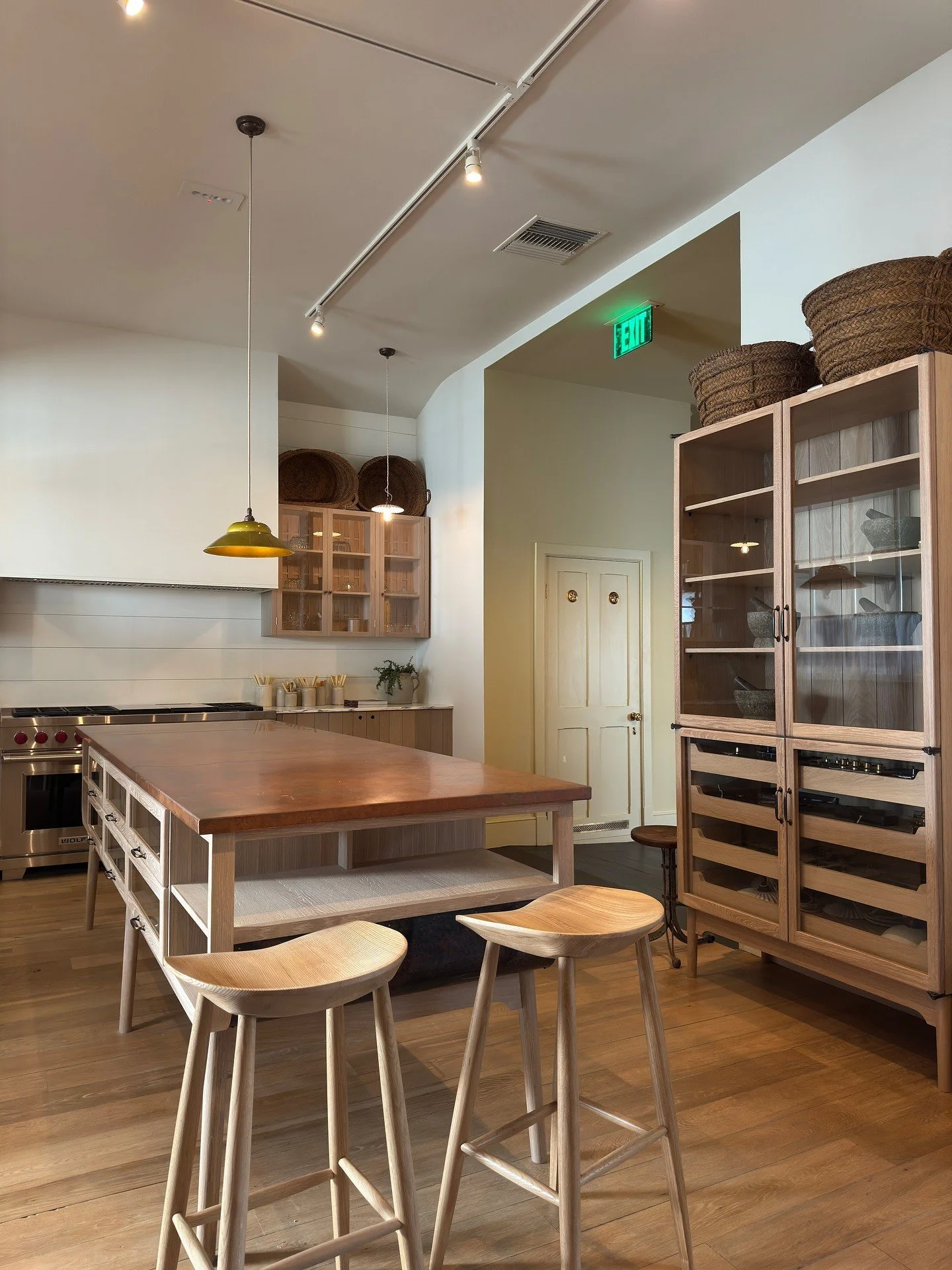 Wood dining table and stools beside pale glass-front cabinets