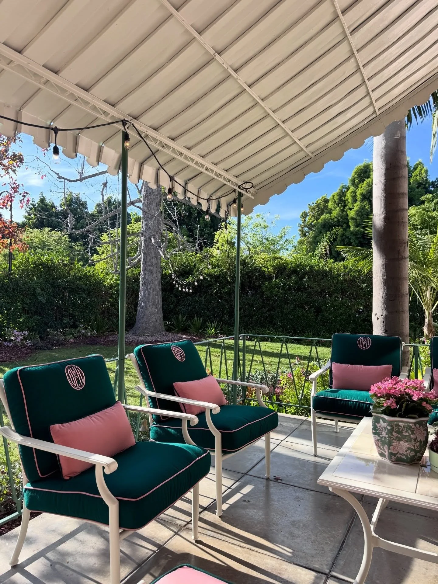 Green cushioned chairs beneath a white covered veranda