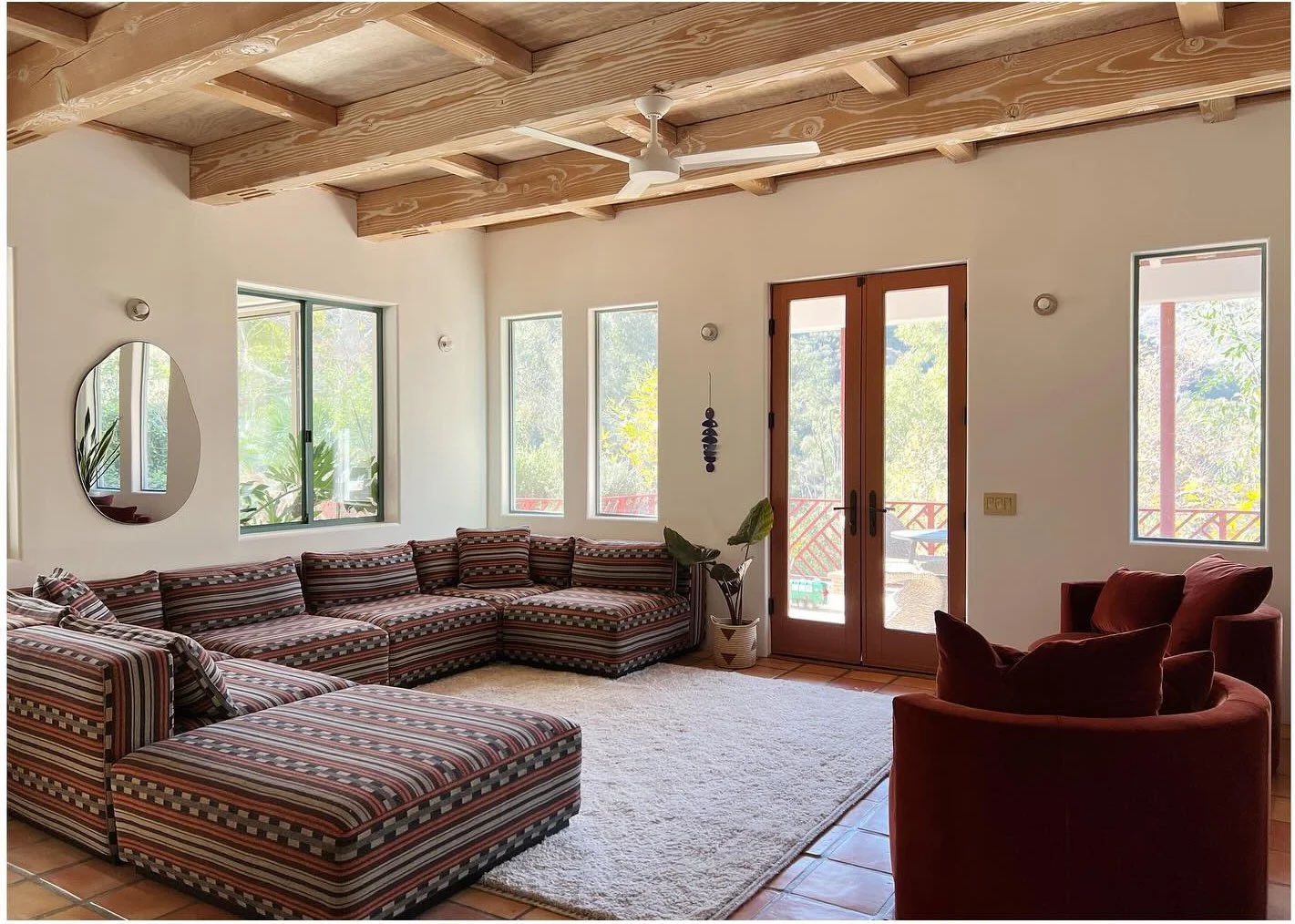 Patterned sectional seating and rust-colored armchair beneath exposed wood beams