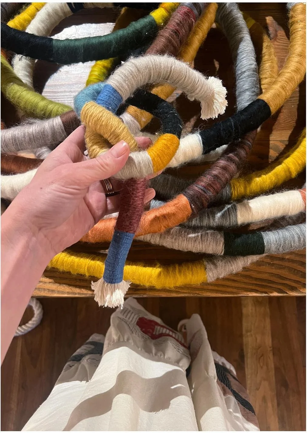 Hand holding a loop of wrapped multicolored fiber sculpture