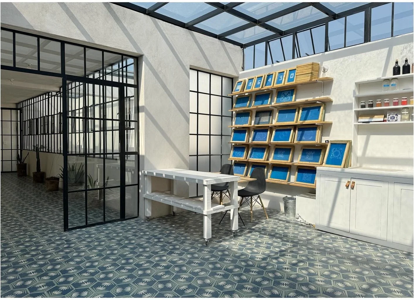 Bright tile showroom with black-framed glazing and blue display shelves