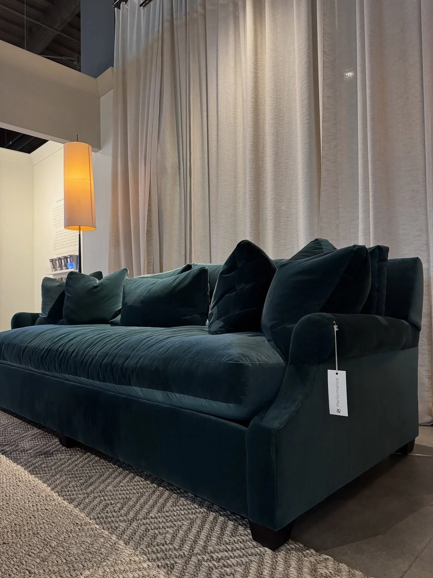 Deep green velvet sofa in front of pale curtains