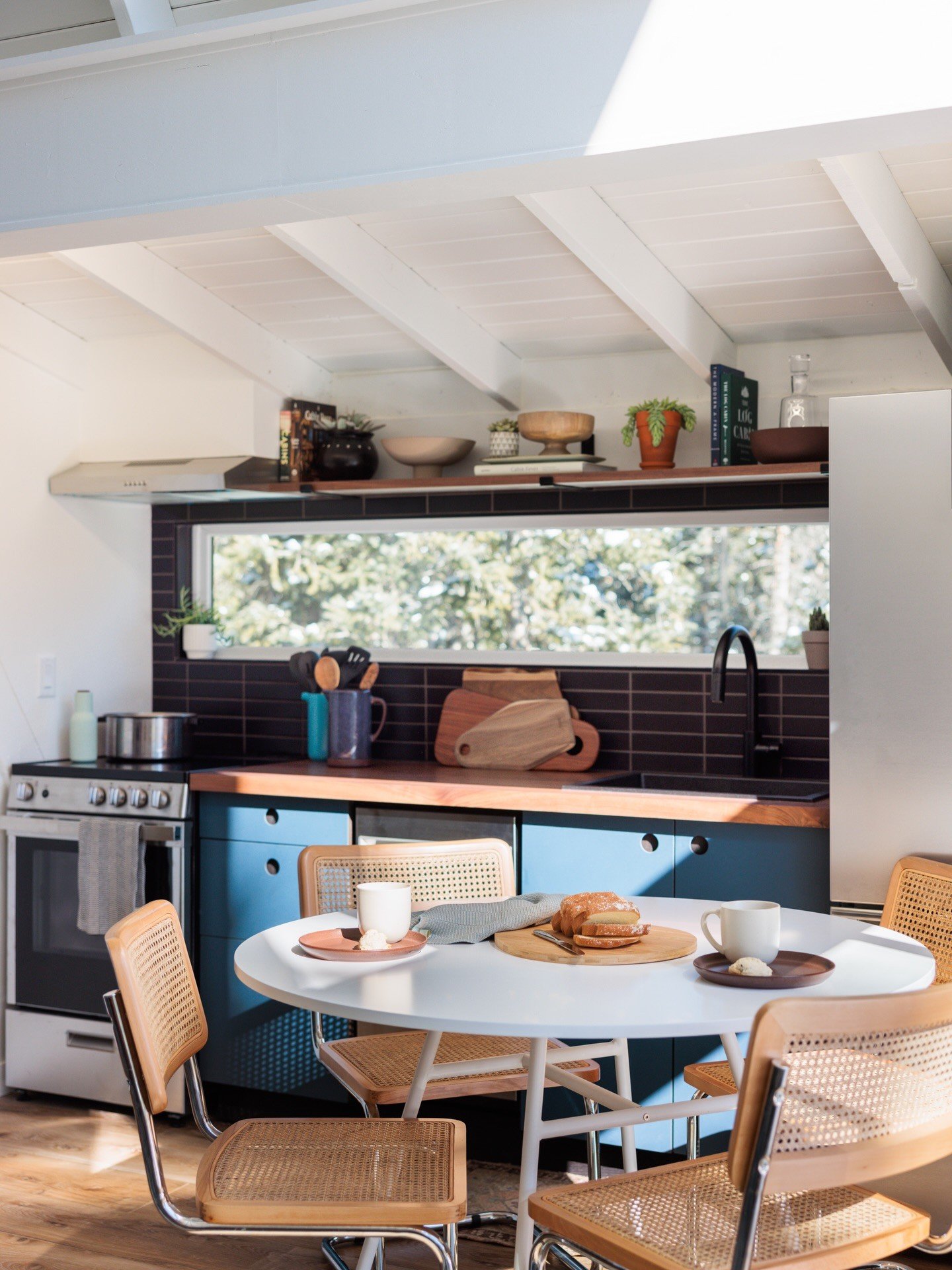Wood dining table beside dark kitchen cabinets and a patterned backsplash