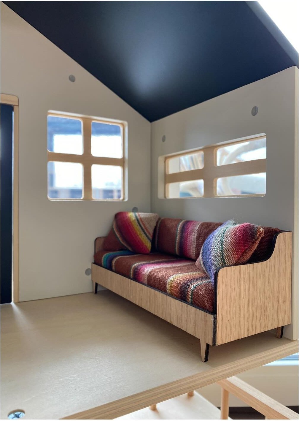 Miniature striped sofa beneath small windows and a dark blue ceiling