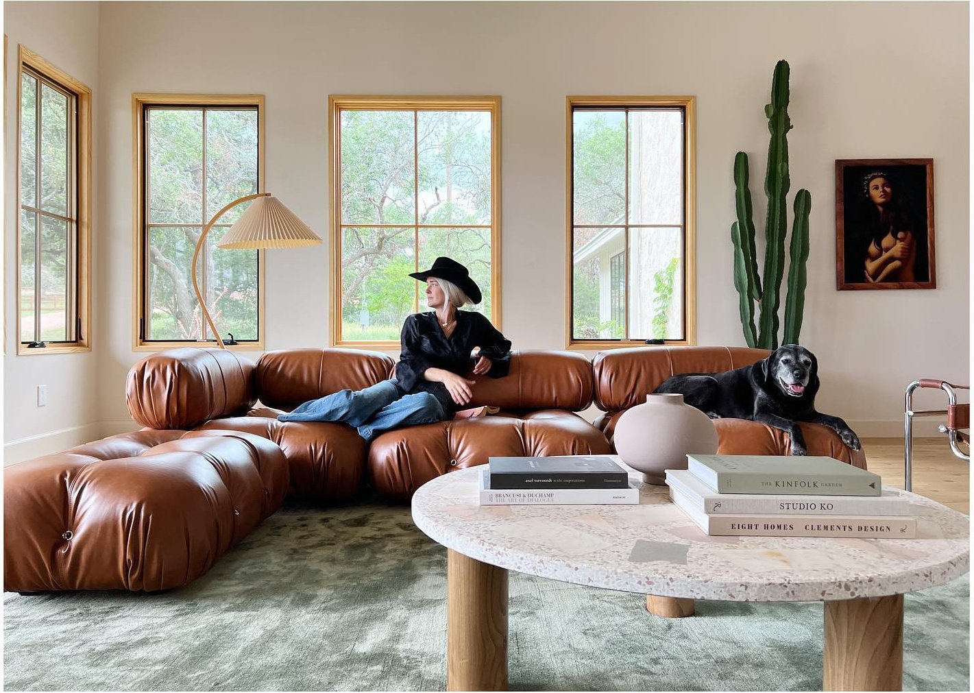 Designer in a layered living room with caramel leather seating and a round pale table